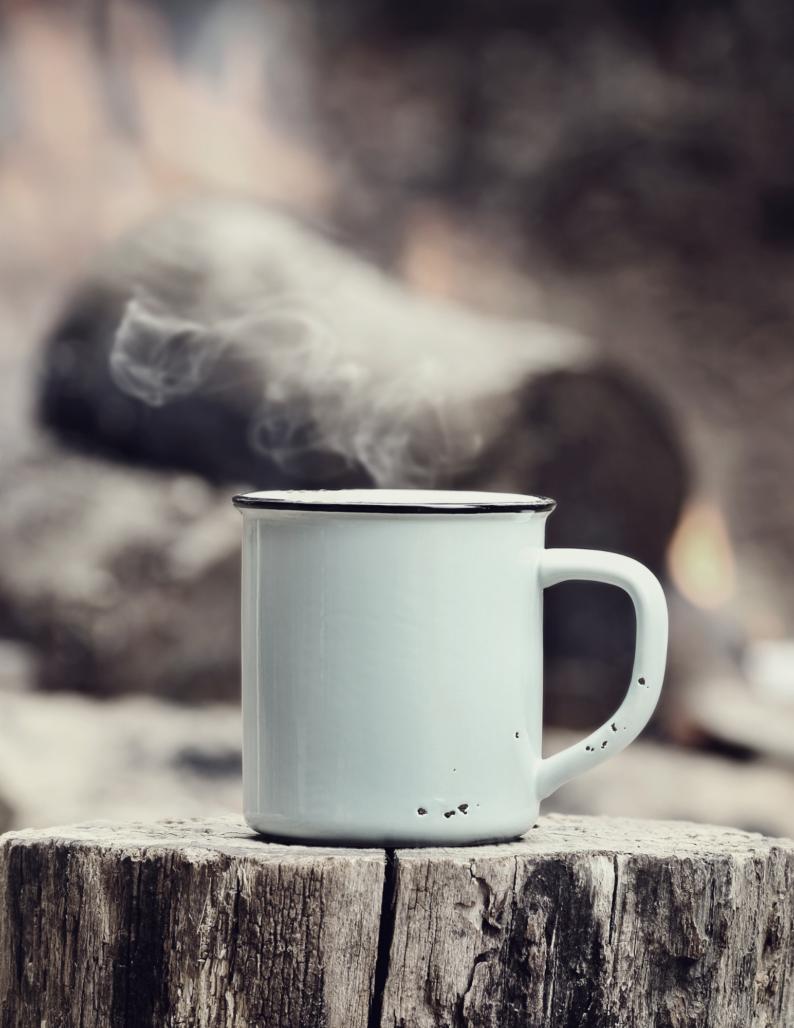 Steaming coffee in an enamel mug beside a morning fire in an Idaho pine forest
